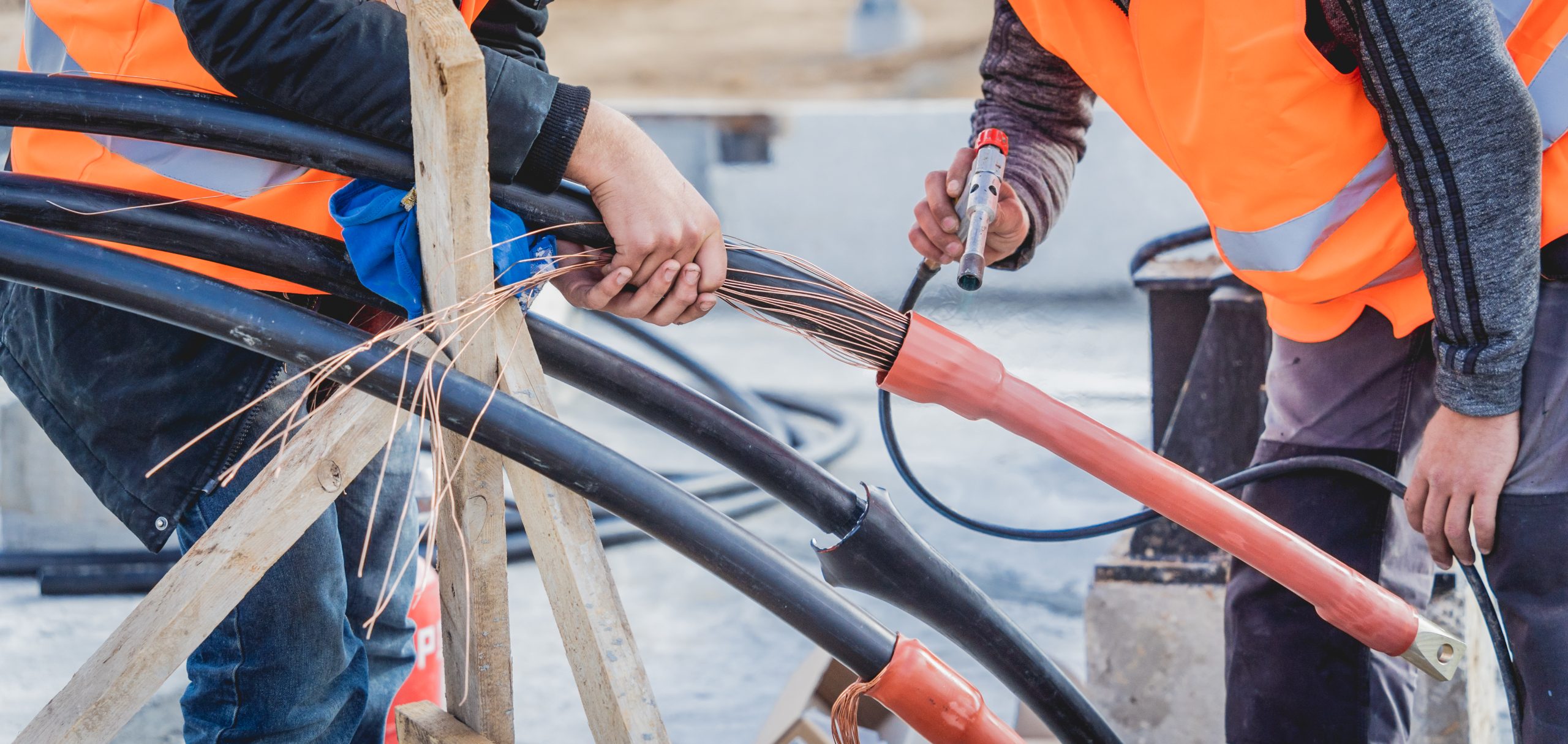 Two electrician builder workers installing high-voltage cable.